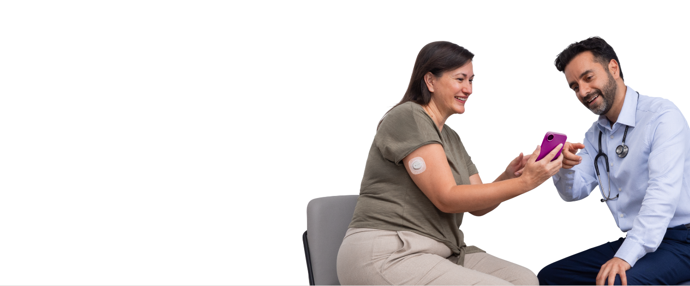 Woman wearing Dexcom G7 CGM sensor on arm and reviewing glucose data on the phone with her doctor.