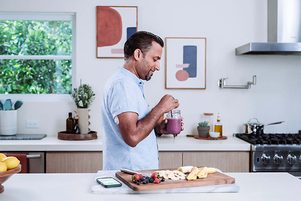 Man in the kitchen wearing Dexcom G7 sensor and managing his diabetes