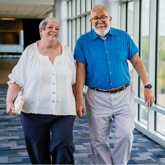 Man and woman holding hands and walking in a hospital hallway