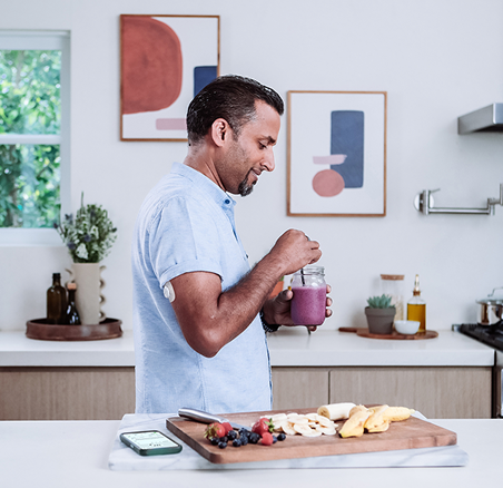Man making a smoothie while wearing the Dexcom G7 15 Day Sensor